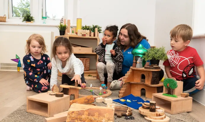 Key worker and children playing with wooden toys at Kiddi Caru Day Nursery Preschool Downend Road Bristol