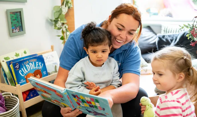 Key worker reading a book with a child at Kiddi Caru Day Nursery Preschool Soundwell Bristol