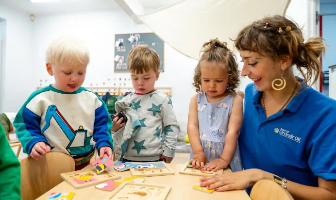 Key worker with childen playing with wooden animal pictures at Kiddi Caru Day Nursery Preschool Brislington Bristol