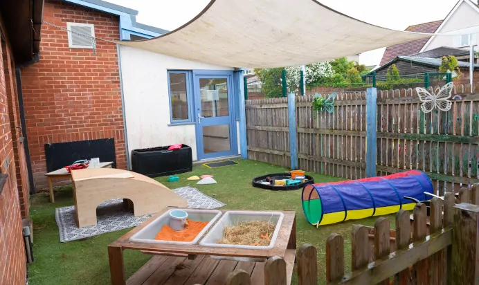 Outdoor play area with wooden slide tunnel and sand pit at Kiddi Caru Day Nursery Preschool Coronation Road Downend Bristol