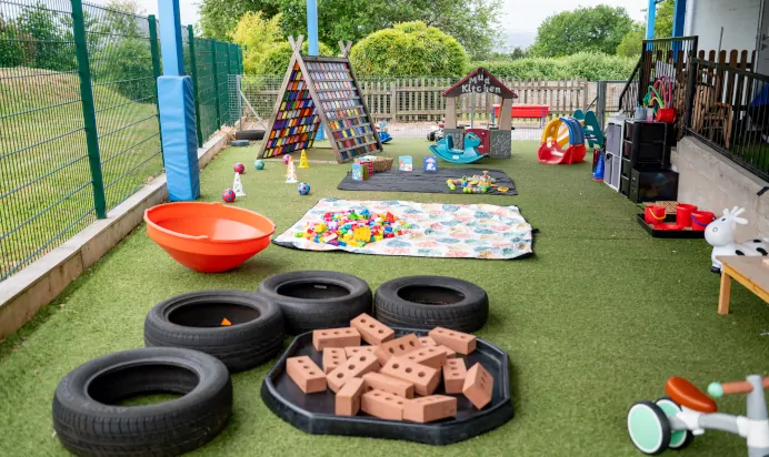 Outdoor play area with tyres blocks sand and slide at Kiddi Caru Day Nursery Preschool Brislington Bristol