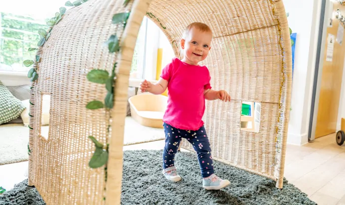 Small child walking and smiling at Kiddi Caru Day Nursery Preschool Soundwell Bristol