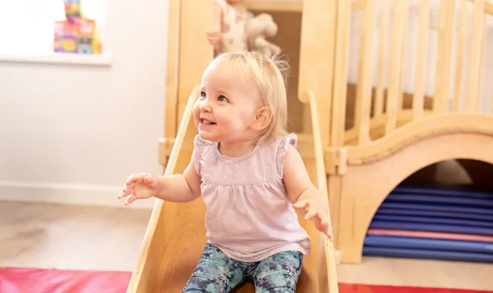 Child smiling on slide at The Elan Day Nursery Haywards Heath