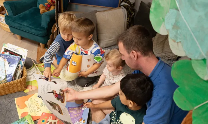 Key worker reading book to children at The Elan Day Nursery Haywards Heath