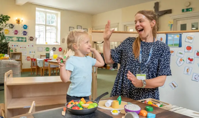 Child high fiving key worker and smiling at The Puddleduck Preschool Priory Road Ascot