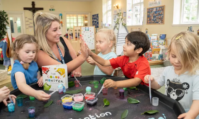 Child high fiving key worker at The Puddleduck Preschool Priory Road Ascot