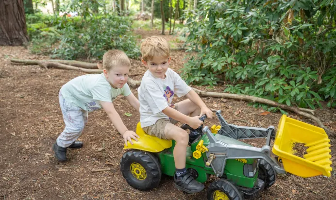 Child pushing friend on toy truck at The Puddleduck Preschool Priory Road Ascot