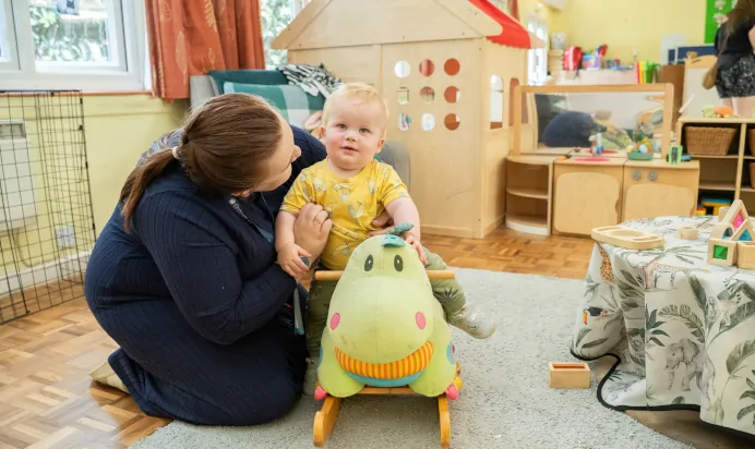 Child sitting on rocking chair with key worker at The Puddleduck Day Nursery St Martins Church Ascot