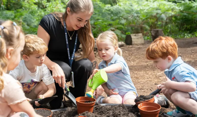 Children collaborating in woods with key worker at The Puddleduck Preschool Priory Road Ascot