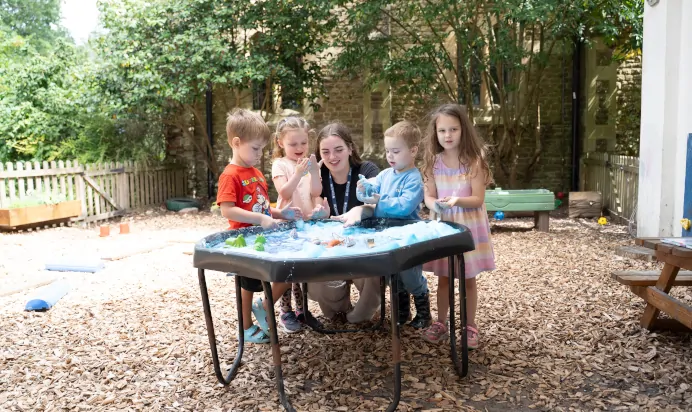 Children learning with key worker outside at The Puddleduck Preschool Priory Road Ascot