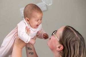 Baby held up in the air, smiling at mum