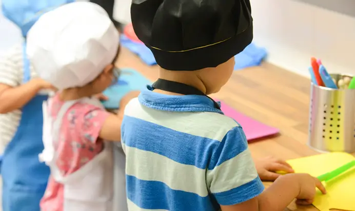 Two children in hats engaged in classroom activities.