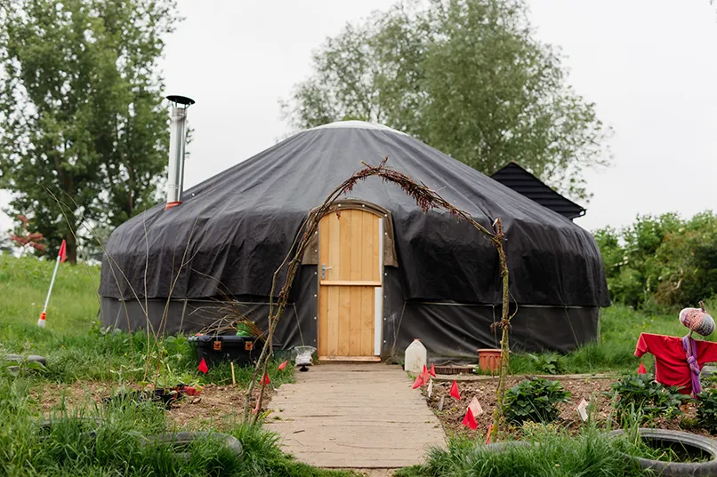A dome-shaped structure with a wooden door, surrounded by a garden