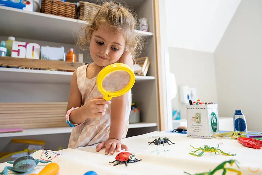 Girl looking at plastic ladybird through a magnifying glass