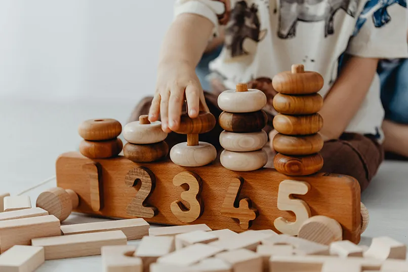 Child playing with wooden numbers and stacking rings.