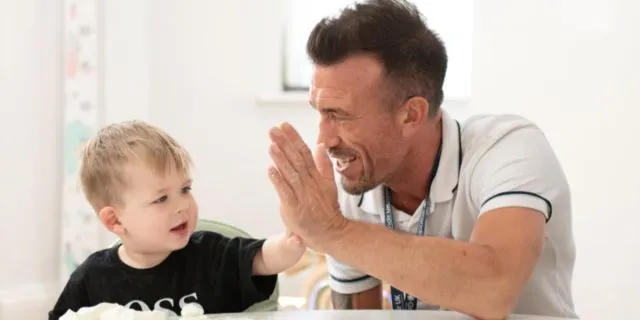 nursery worker and child high five at Grandir UK nursery